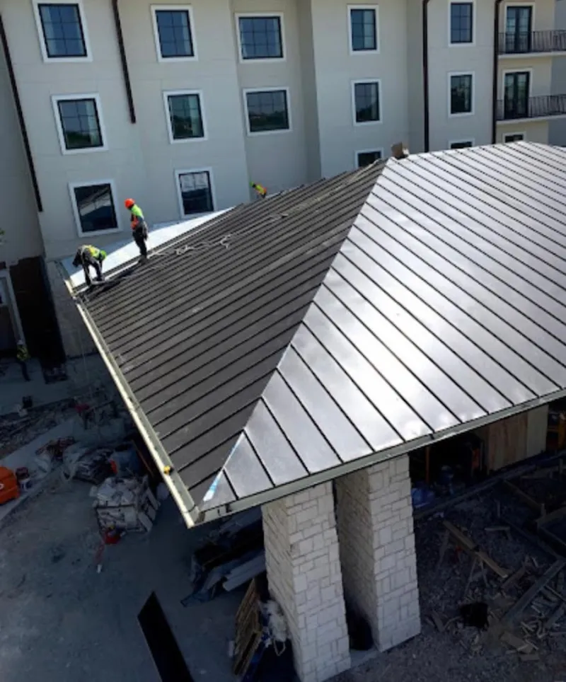 Crew installing standing seam metal roof panels on a commercial project in Chanute
